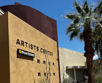 a building with palm trees and a sign that says artists center